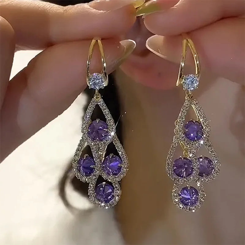 Brincos de gota com cristal roxo da Rose & Oliver, elegantes e brilhantes, pendurados em fio de metal prateado.