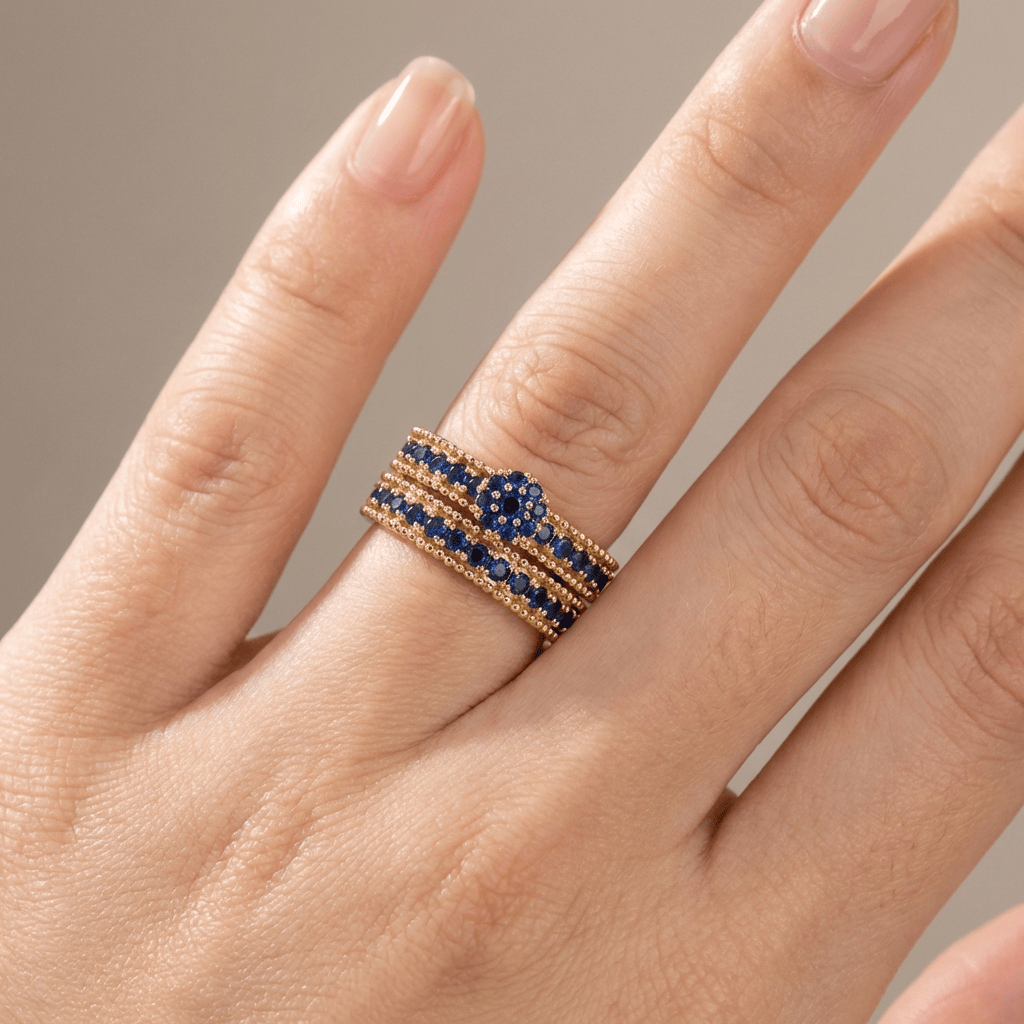 Conjunto de anéis empilháveis em ouro com safiras azuis da marca Rose & Oliver, detalhes de joalheria elegante e delicada.