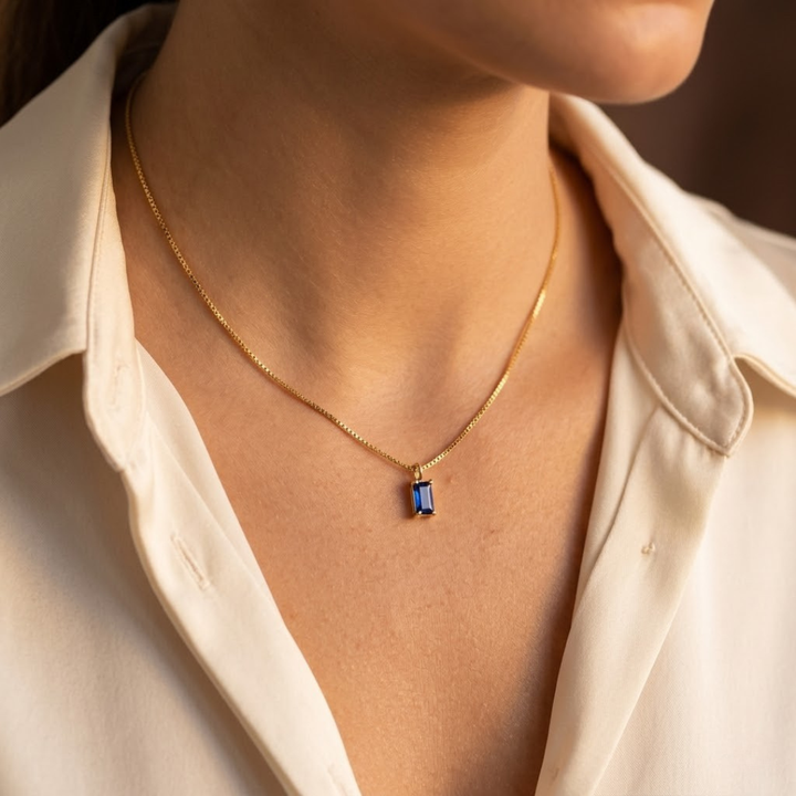 Colar minimalista em ouro com safira, marca Rose & Oliver, exibindo design delicado e elegante em imagem clara.
