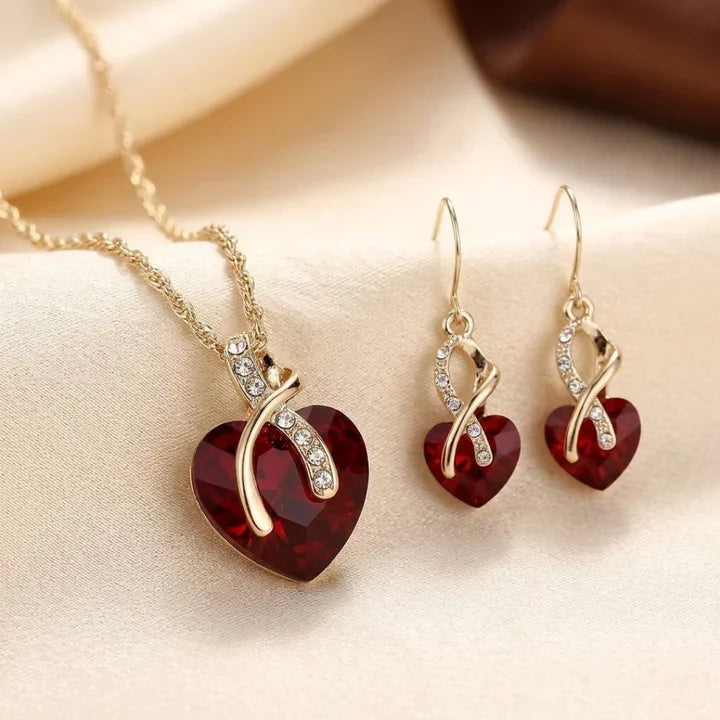 Conjunto de joias Rose & Oliver com coração torcido dourado e rubis vermelhos, incluindo colar e brincos elegantes para ocasiões especiais.