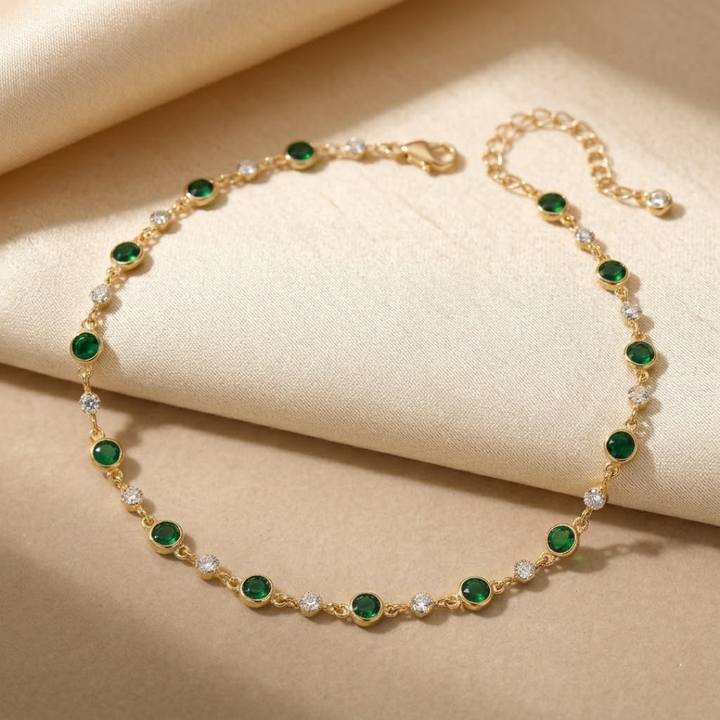 Colar de gargantilha com esmeraldas verdes e detalhes em ouro, da marca Rose & Oliver, exibido em fundo neutro.