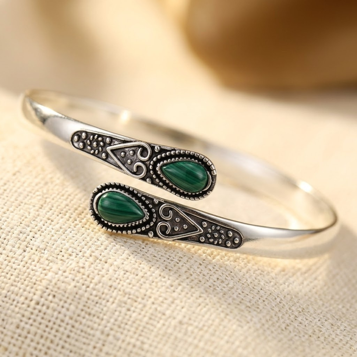 Pulseira vintage de prata com detalhes em esmeralda, estilo bangle, da marca Rose & Oliver, visível na imagem.
