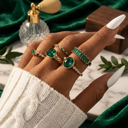 Conjunto de joias com anéis de ouro e esmeralda da Rose & Oliver, incluindo duas peças com detalhes dourados e pedras verdes brilhantes.