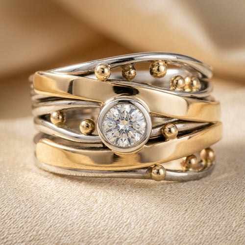 Anel Rose & Oliver com bezel em prata e ouro, detalhe delicado e acabamento brilhante em uma mão feminina.