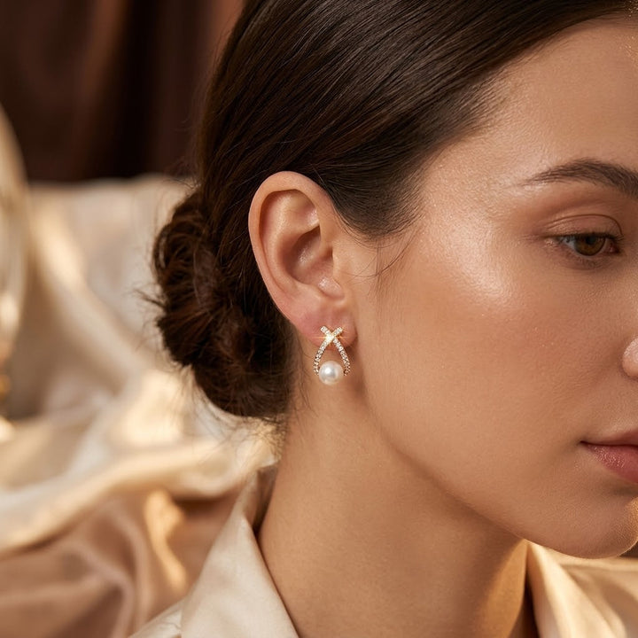Brincos de ouro com design cruzado e pérolas, estilo joia delicada, marca Rose & Oliver, detalhes visíveis na imagem.