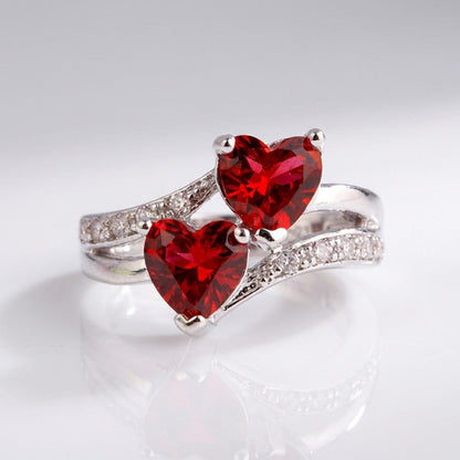 Anel de prata Rose & Oliver com dois corações vermelhos entrelaçados, design delicado para uso diário e ocasiões especiais.