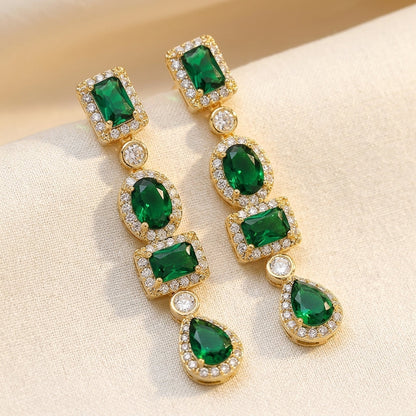 Brincos de ouro com esmeraldas em múltiplas formas, estilo gota, da marca Rose & Oliver, detalhes elegantes e sofisticados.