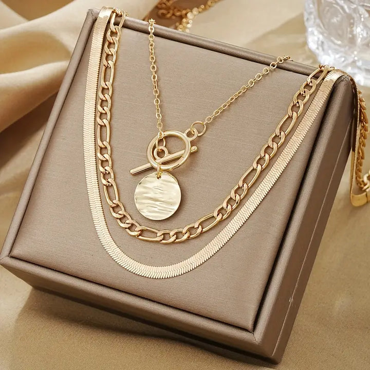 Colar dourado em camadas com textura de moedas, estilo contemporâneo, da marca Rose & Oliver, em detalhe na imagem.