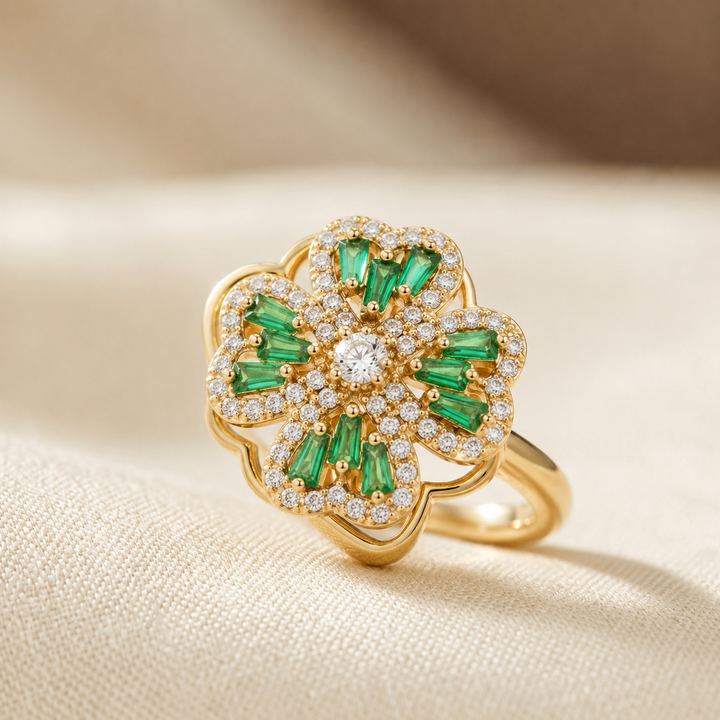 Anel floral de ouro com esmeraldas verdes, da marca Rose & Oliver, exibido em destaque na imagem.