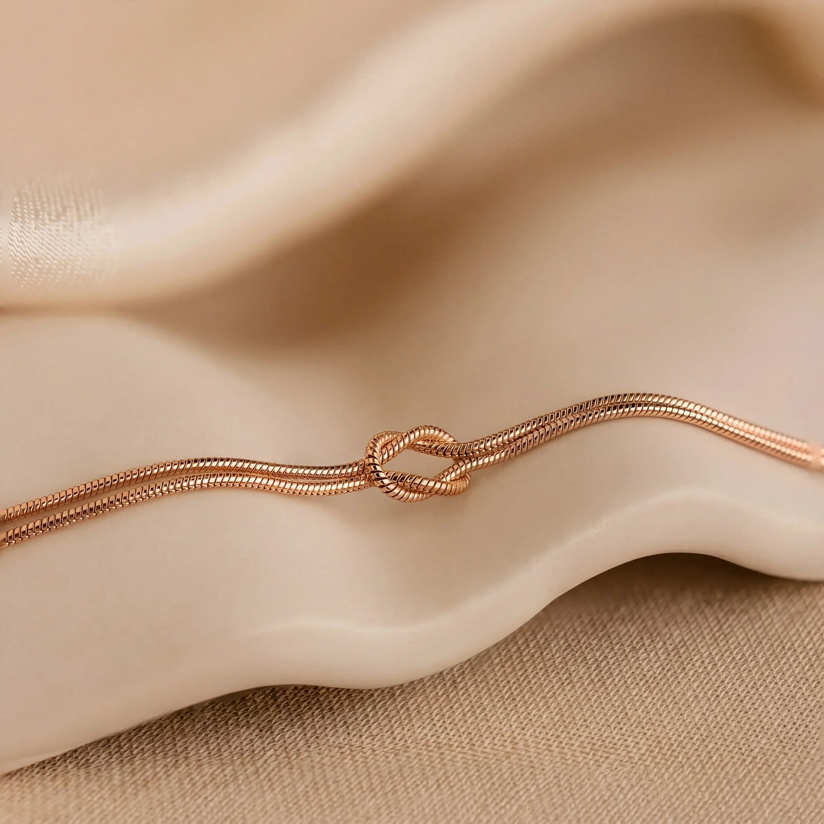 Pulseira Forever Knot da Rose & Oliver em tom dourado rosado, símbolo de conexão e amizade, com design elegante e delicado.