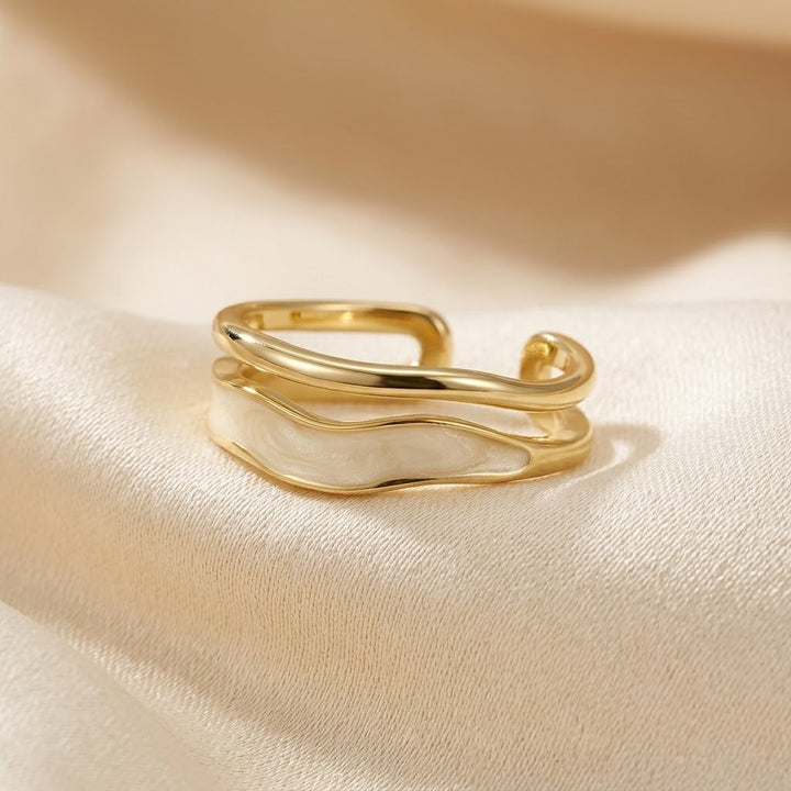 Anel dourado Rose & Oliver com design escultórico envolvente, destaque para acabamento brilhante e forma artística.