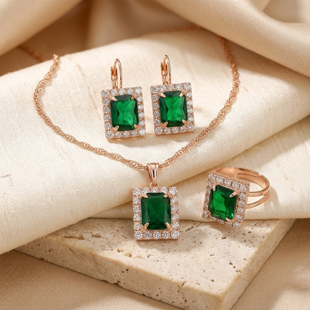 Conjunto de joias dourado com esmeraldas retangulares, da marca Rose & Oliver, exibindo colar e brincos elegantes.