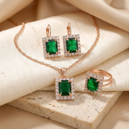 Conjunto de joias dourado com esmeraldas retangulares, da marca Rose & Oliver, exibindo colar e brincos elegantes.