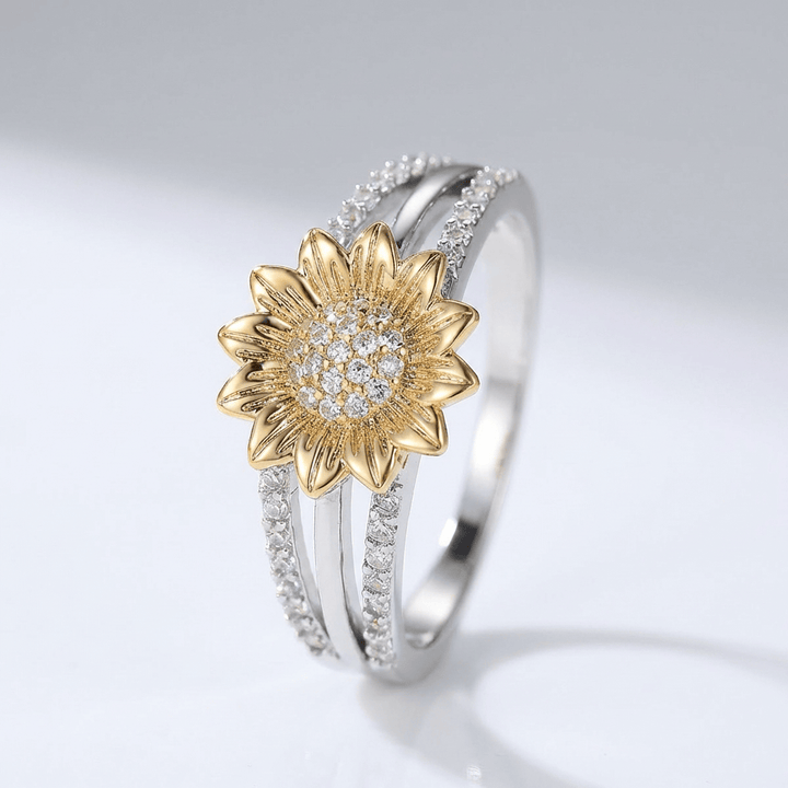 Anel de prata e ouro com design de girassol e diamantes, da marca Rose & Oliver, destacando detalhes brilhantes e delicados.