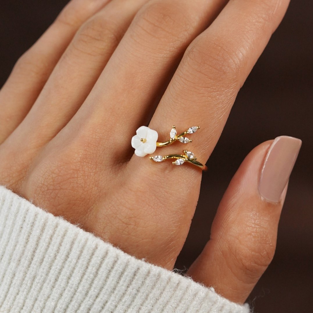 Anel aberto rosa e dourado com flor e folhas em detalhes delicados, da marca Rose & Oliver, sobre fundo branco.